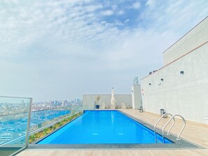A rooftop pool with a city view, surrounded by a modern building with a concrete exterior. - R Lindo departamento 1BR en Miraflores (Lima)