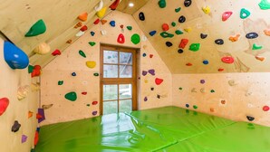 Une salle d’escalade dotée d’un sol recouvert d’un tapis vert et de prises d’escalade colorées fixées aux murs.