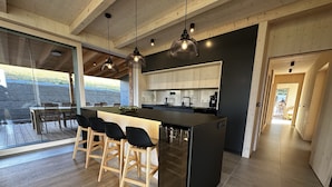 A modern kitchen with a central island, bar stools, and pendant lighting. - Holiday Home in Roprachtice With Sauna & Jacuzzi (Roprachtice)