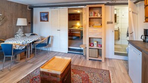 A compact living space with a dining area, a small kitchen, and a bedroom. - Appartementen Am Forstweg Yalet (Brilon)
