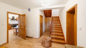 A hallway with wooden flooring, a wooden staircase, and a round wooden stool. - Villa in Varvazov With Garden Retreat (Varvažov)