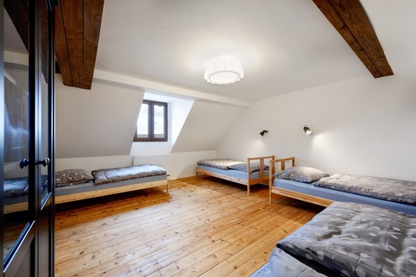 A dormitory room with wooden floors, three bunk beds, a skylight, and a ceiling light fixture. - Villa in Varvazov With Garden Retreat (Varvažov)