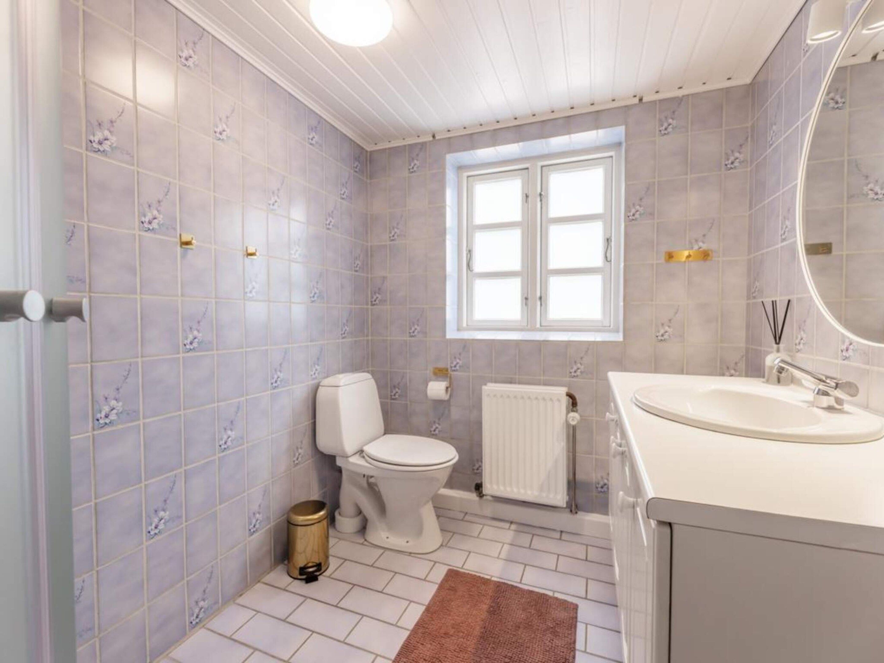 A bathroom with a toilet, sink, and window.