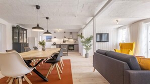 A modern open-plan living space with a dining area, kitchen, and seating area. - 5 Star Holiday Home in Hjorring (Hjørring)