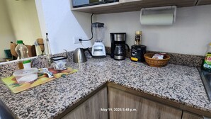 Una cucina con piano di lavoro in granito, una moka, un frullatore, un bollitore, un tostapane e un lavandino.
