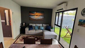 Un soggiorno con un divano grigio, un tavolino da caffè e un tappeto. Al muro, un quadro raffigura un tramonto.