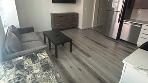 Ein modernes Wohnzimmer mit einer Couch, einem Couchtisch und einem an der Wand befestigten Flachbildfernseher.