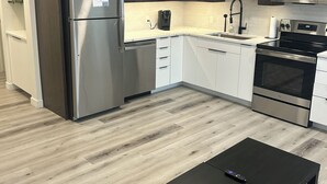 Eine moderne Küche mit Edelstahlgeräten, weißen Schränken und Holzboden.