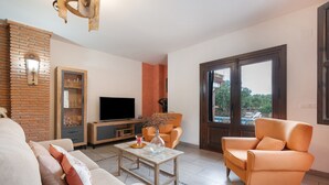 Ein Wohnzimmer mit Sofa, Sessel, Couchtisch, TV-Möbel und einem großen Fenster.