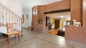 Ein Wohnzimmer mit Kamin aus Backstein, einer Holztreppe und einem Essbereich.