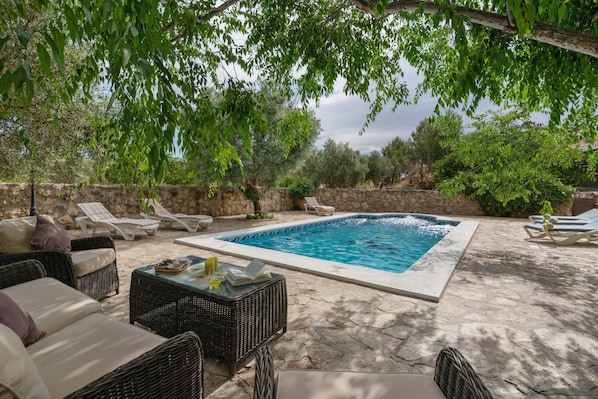 Una piscina con sillones de baño y mobiliario de mimbre.