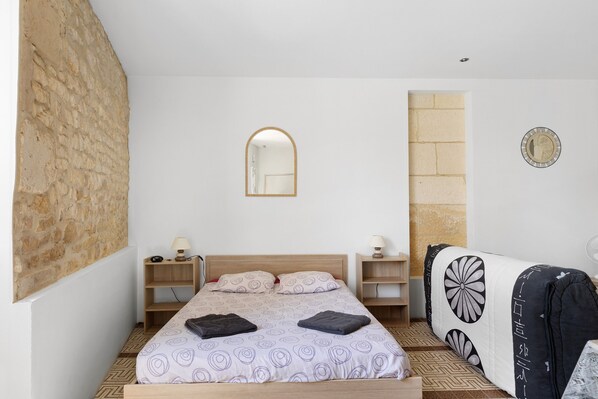 A bedroom with a bed, bedside tables, a mirror, and a wardrobe.
