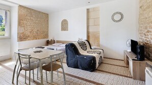 Una habitación con una mesa de comedor, sillas, un sofá, un televisor y una pared de piedra.