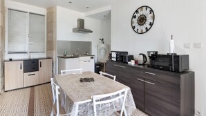 Una cocina compacta con una mesa de comedor, armarios, un microondas y un reloj de pared.