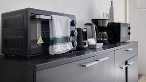 Una cocina con tostadora, cafetera y hervidor sobre una encimera.