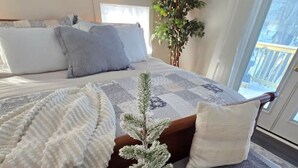 A bedroom with a bed, a small potted plant, a tray with a plant, and a gray bench. - The Jefferson Guest House, Spacious, Special Views (Litchfield)