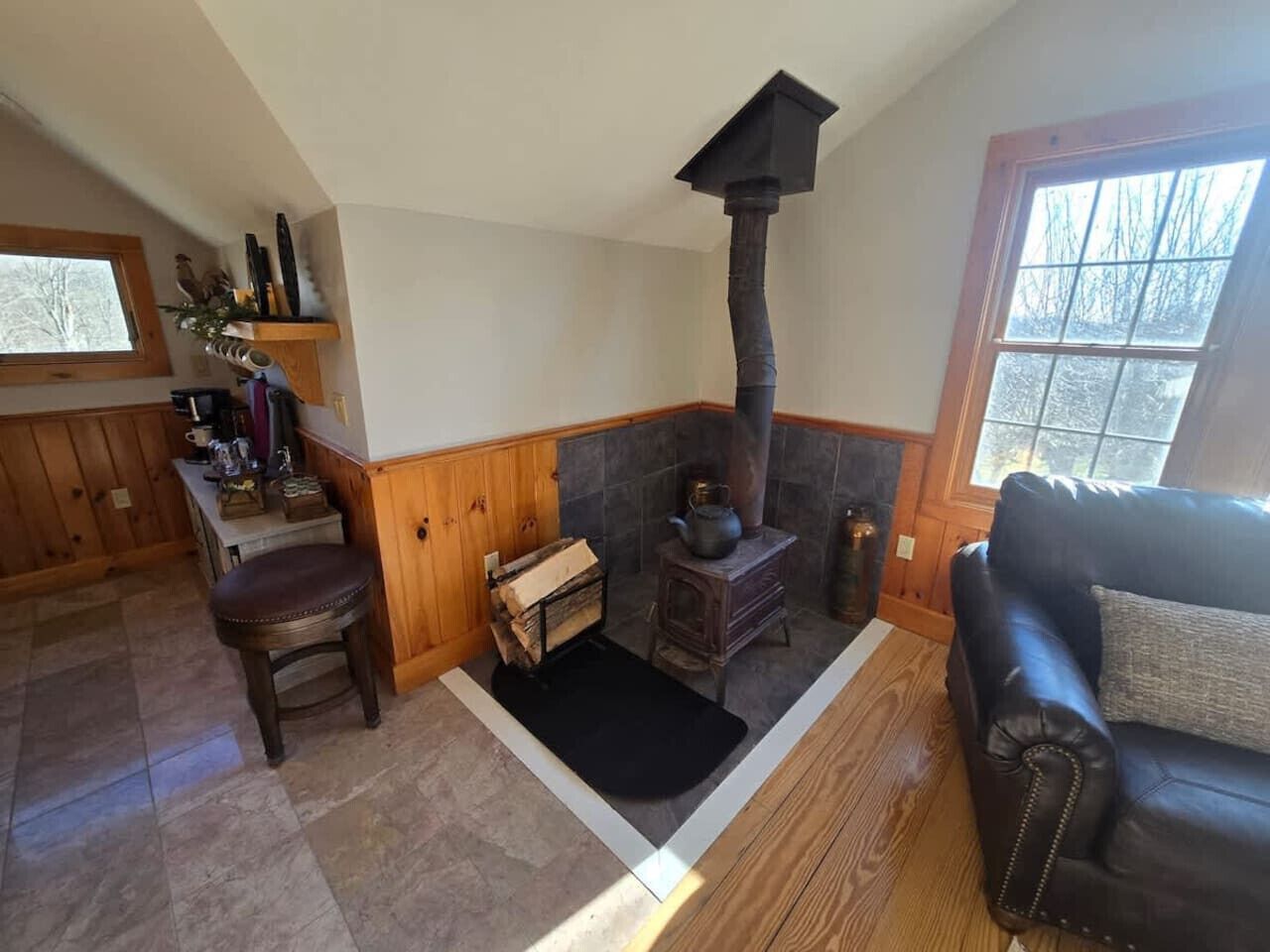 A cozy living room with a fireplace, wooden furniture, and a window.