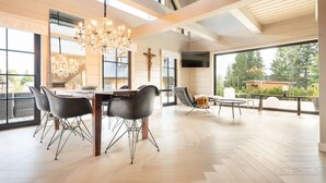A spacious dining area with a wooden table, black chairs, and a chandelier. - Villa in Abertamy Near Klinovec Ski Resort (Abertamy)