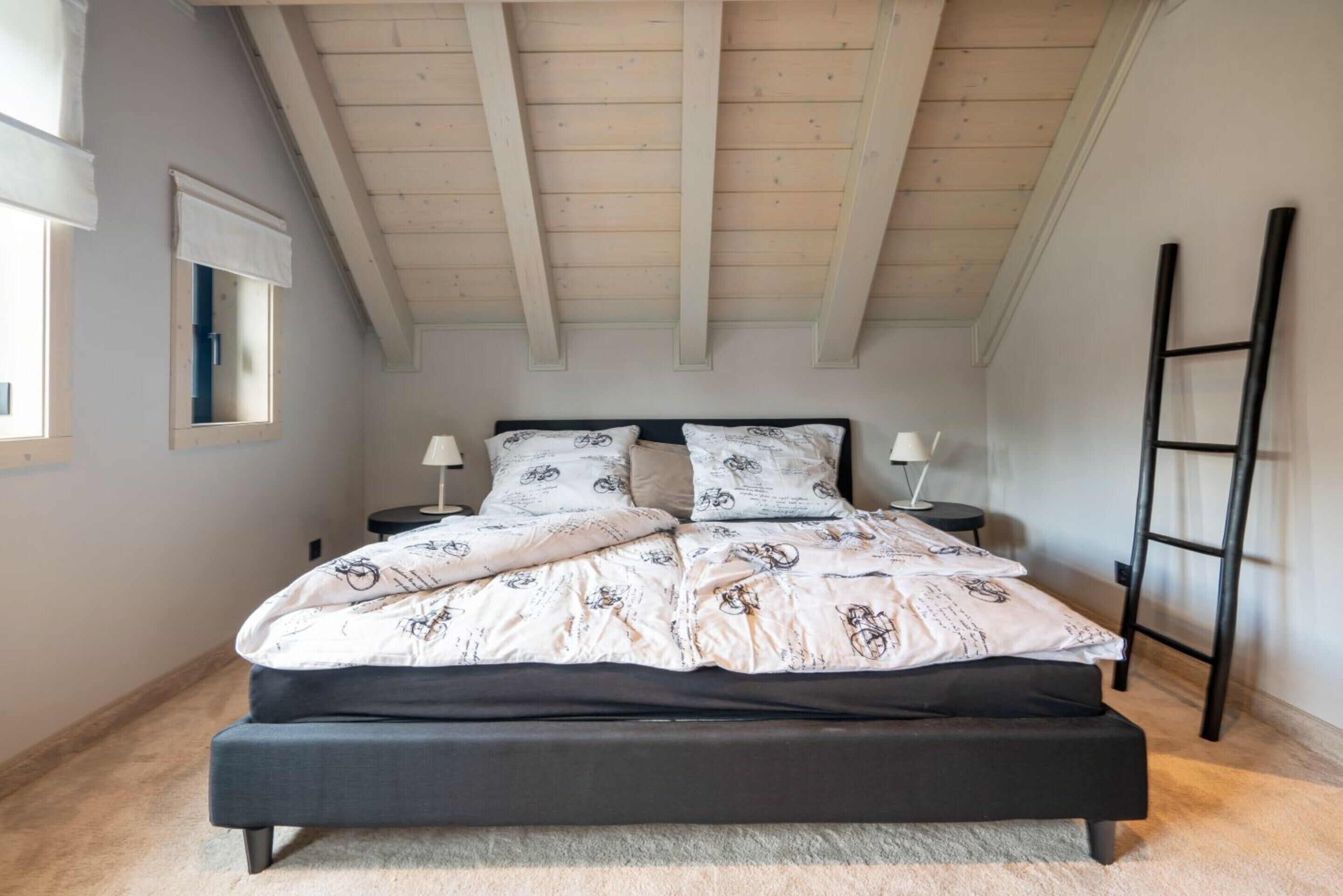 A bedroom with a bed, nightstands, a ladder, and a window.