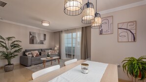 A modern living room with a dining table, sofa, and potted plants. - Elegant Apartment in a Prime Location (Marbella)