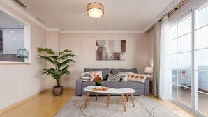 A modern living room with a sofa, a coffee table, a potted plant, and a large window. - Elegant Apartment in a Prime Location (Marbella)