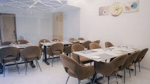 A conference room with multiple tables and chairs, glass partitions, and artwork on the walls. - Hotel Green One Earth (Amritsar)