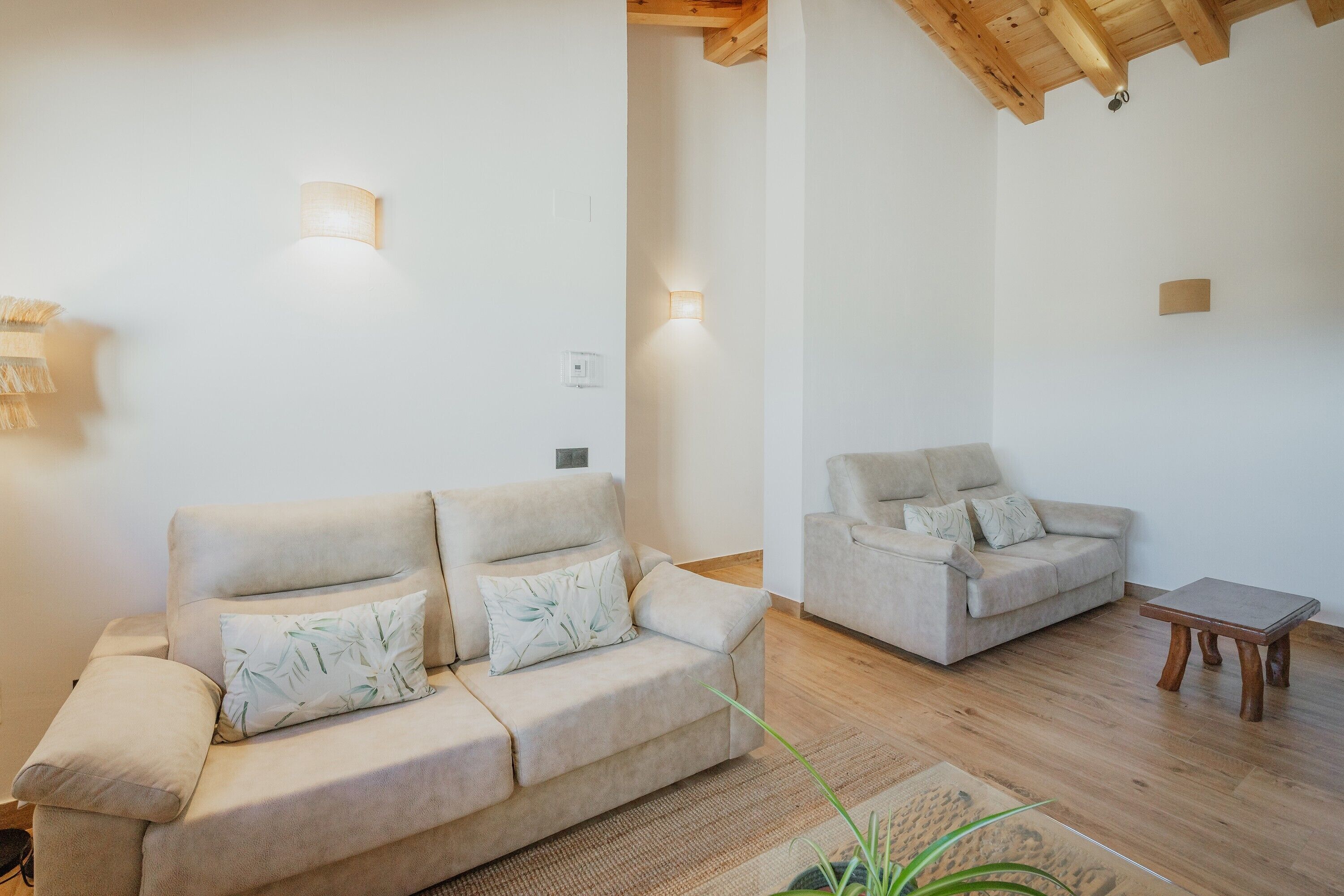 A living room with two sofas, a wooden coffee table, and wall-mounted lighting.