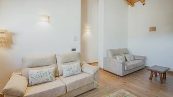A living room with two sofas, a wooden coffee table, and wall-mounted lighting.