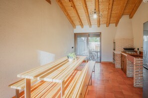 Una cocina con vigas de madera, un horno de ladrillo y una larga mesa de madera.