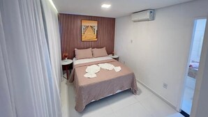 Een hotelkamer met een bed, nachtkastjes, een schilderij aan de muur en een airconditioner.