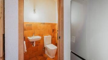 Een badkamer met een wastafel, toilet en spiegel.
