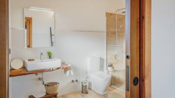 A modern bathroom with a wooden vanity, a white sink, a toilet, and a glass shower enclosure.