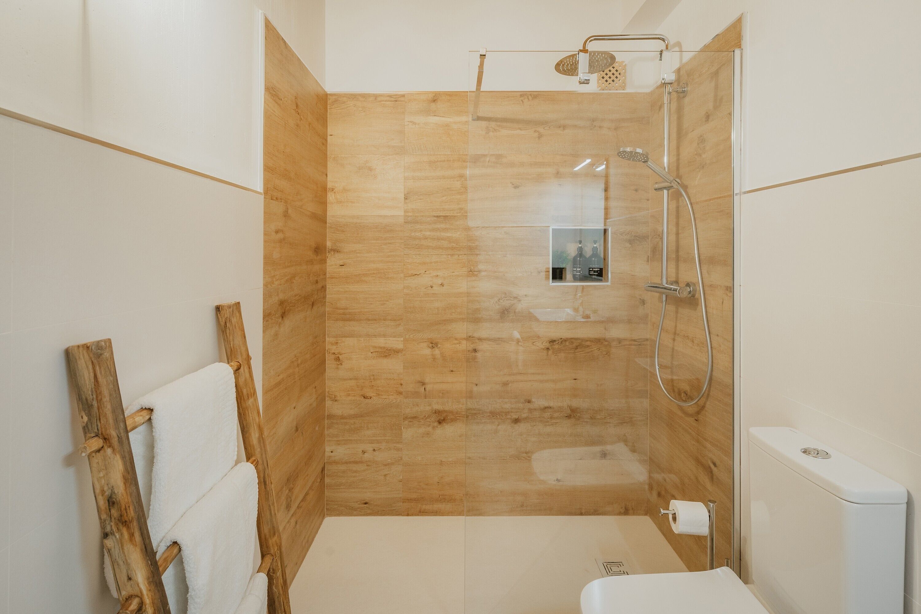 Een moderne badkamer met een houten wand, een douche en een toilet.