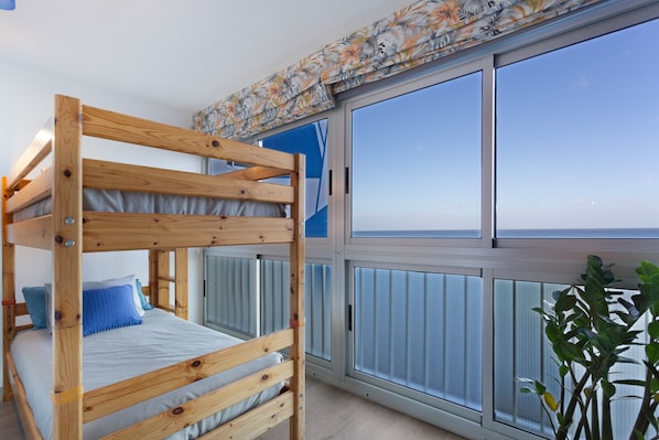 A bunk bed room with a large window and a view of the sea.