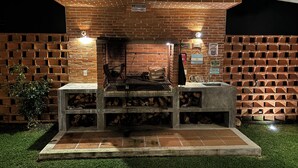 An outdoor barbecue area with a brick wall, a grill, and a sink. - Casa en Lomas de Cocoyoc, Alberca, Pet friendly. (Fraccionamiento Lomas de Cocoyoc)
