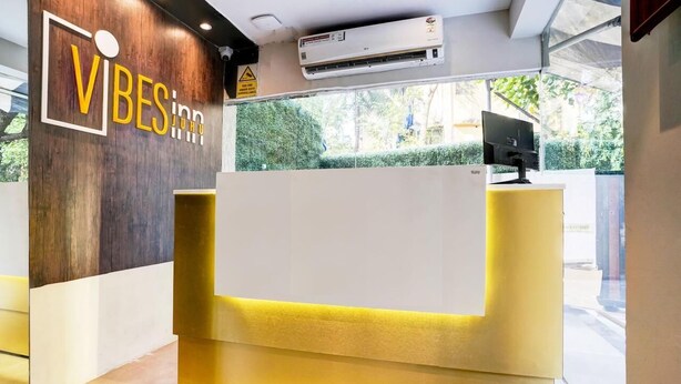 A reception desk with a wooden wall and a sign that reads "VIBES inn JUHO". - Vibes INN (Mumbai)