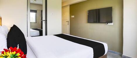 A hotel room with a bed, a TV mounted on the wall, and a door leading to a bathroom.