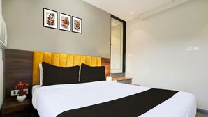 A neatly made bed with a white and black bedspread, a wooden headboard, and a nightstand with a vase of flowers. - Vibes INN (Mumbai)