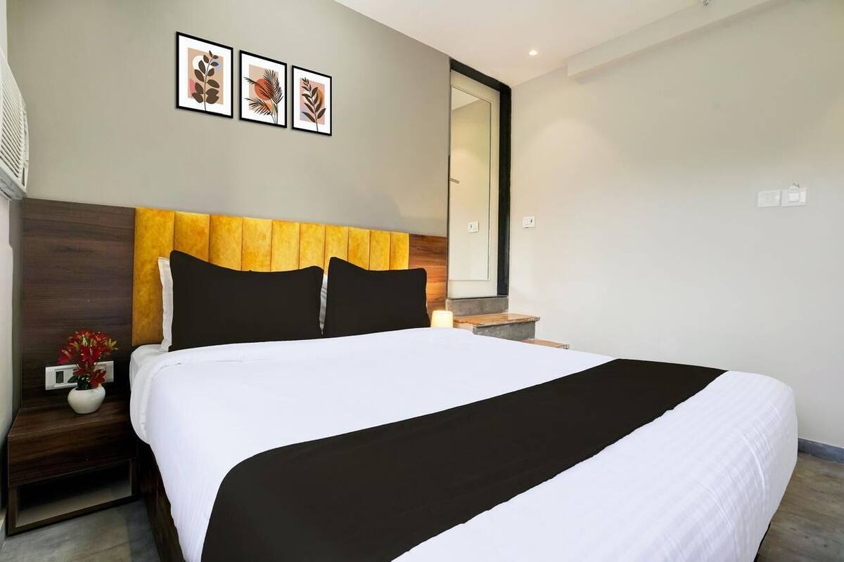 A neatly made bed with a white and black bedspread, a wooden headboard, and a nightstand with a vase of flowers.