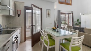 A modern kitchen with a glass dining table, white chairs, and a beige sofa. - Vacation Villa 'Kalima' with Mountain View, Wi-Fi and Air Conditioning (Playa Blanca)