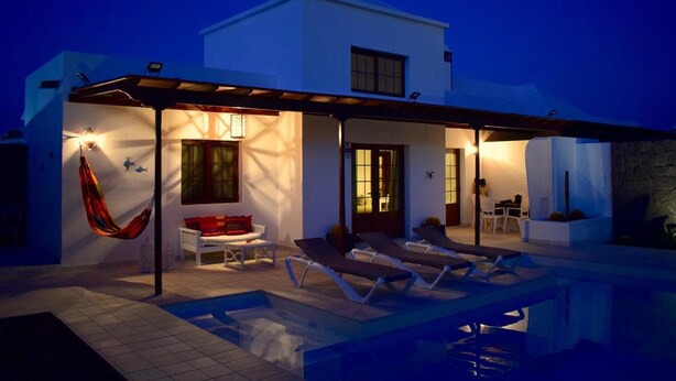 A modern house with a pool, a hammock, and a patio area with lounge chairs. - Vacation Villa 'Kalima' with Mountain View, Wi-Fi and Air Conditioning (Playa Blanca)