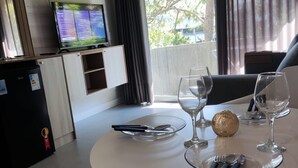 A dining area with a round table set for two, a television on a cabinet, and a refrigerator. - APARTAMENTO MEU LAR LIBERDADE SP (São Paulo)