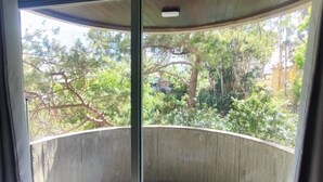 A curved balcony with a glass door, offering a view of trees and buildings. - APARTAMENTO MEU LAR LIBERDADE SP (São Paulo)