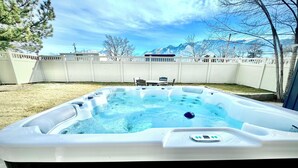 A hot tub in a backyard with a view of mountains in the background. - Luxe 5 BR Family Friendly Oasis-5 King Beds-Hot Tub-Fire Pit-Ski-Hike-Yard Games (Sandy)
