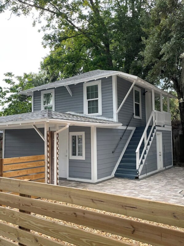 A two-story house with a covered porch, a staircase, and a fenced yard.