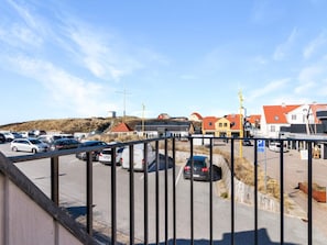 A parking lot with cars and a building with a red roof in the background. - 5 Star Holiday Home in Lokken (Lokken)