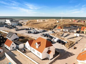 A coastal area with a parking lot, buildings, and a view of the sea. - 5 Star Holiday Home in Lokken (Lokken)