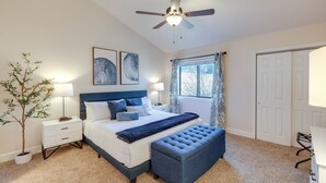 A bedroom with a bed, bedside tables, a ceiling fan, a window with curtains, and a door. - Cozy Flagstaff Condo in Country Club Community! (Flagstaff)
