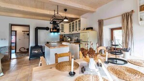 Una cocina acogedora con vigas de madera, una isla central y un comedor con individuales tejidos y velas.