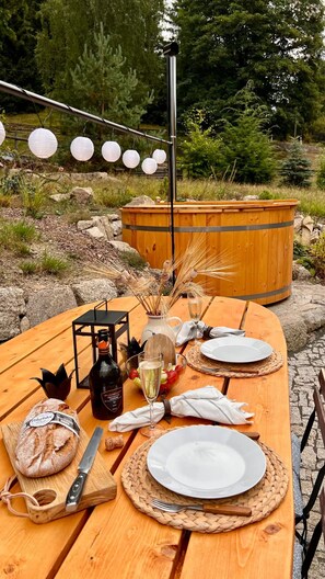 A wooden table set outdoors with plates, cutlery, a bottle, a loaf of bread, and a candle. - Villa in Bohemia With Terrace (Lučany nad Nisou)